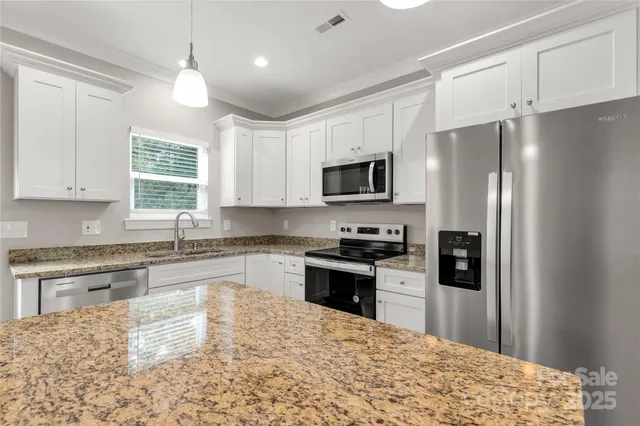 a kitchen with granite countertop a refrigerator stove top oven and sink