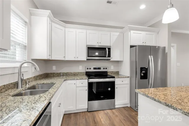 a kitchen with granite countertop a sink stove and refrigerator