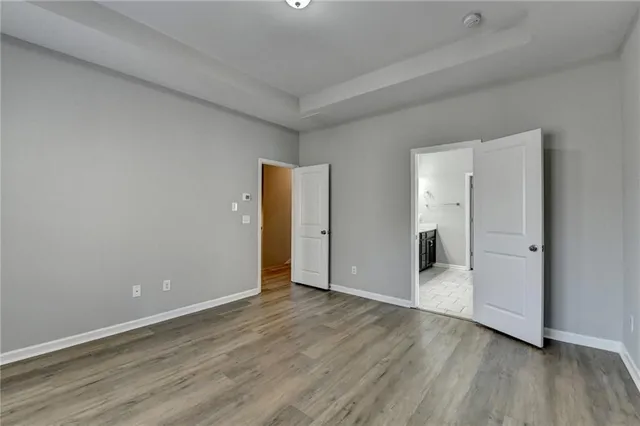 a view of an empty room with wooden floor and closet