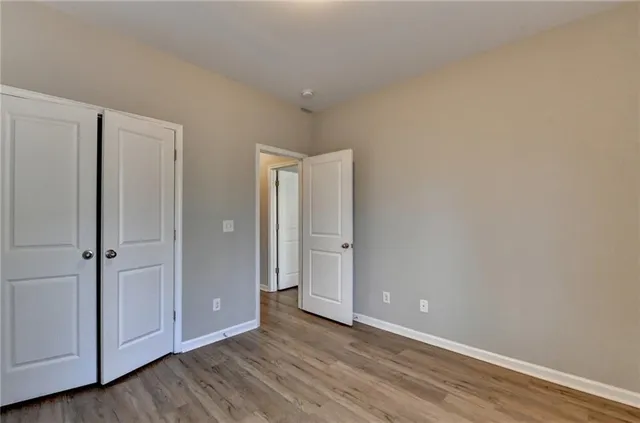 a view of an empty room with closet and wooden floor