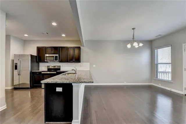 a kitchen with granite countertop stainless steel appliances a sink cabinets and wooden floor