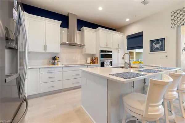 a kitchen with stainless steel appliances a stove a sink refrigerator and white cabinets with wooden floor