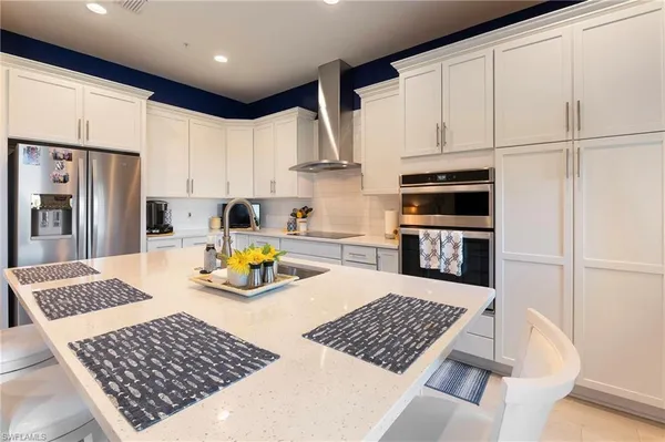 a kitchen with stainless steel appliances granite countertop a stove top oven a refrigerator a sink and white cabinets