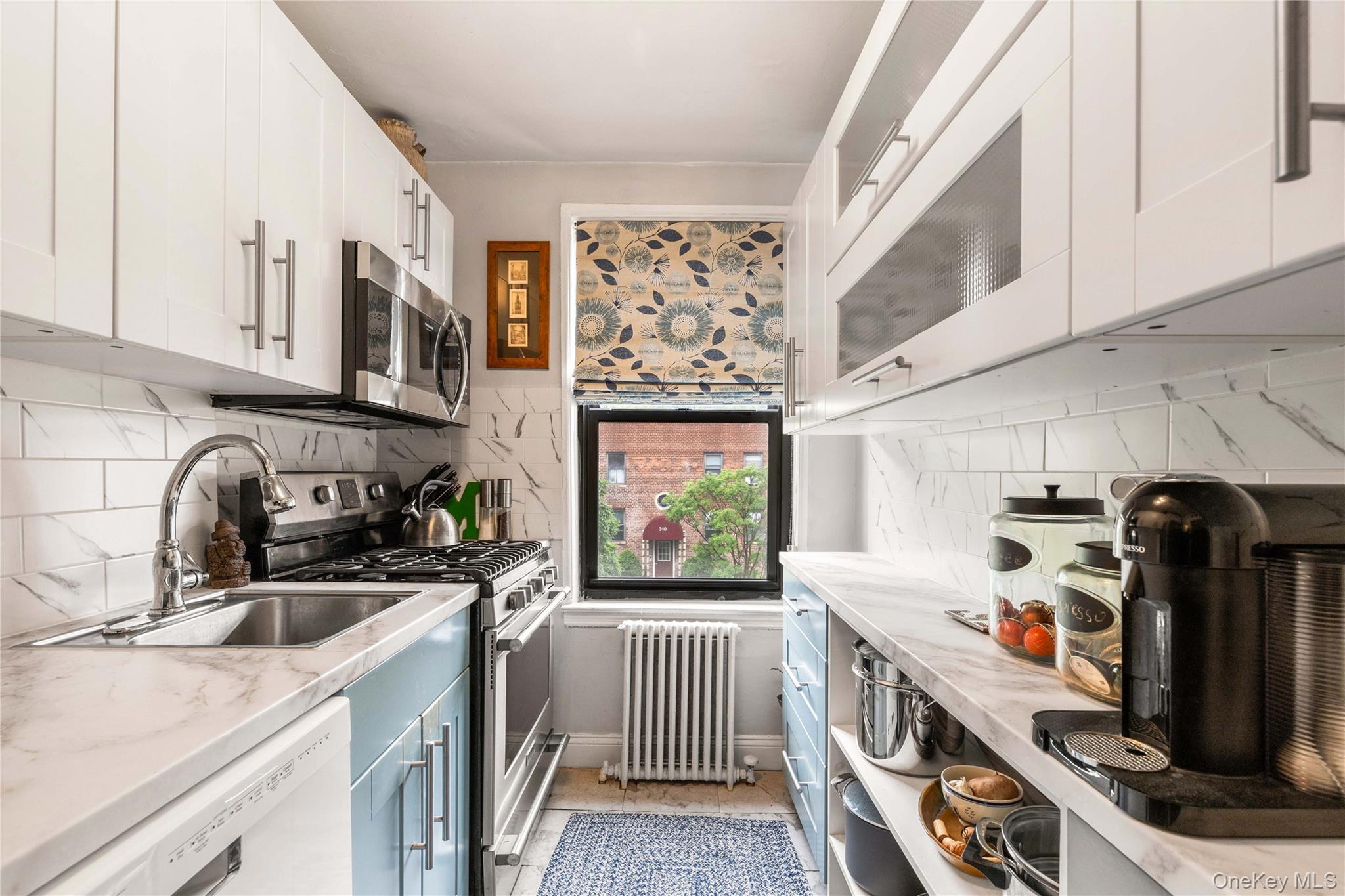 316 Richbell Road, Unit C2 Mamaroneck, NY 10543 - Photo 8 of 13 Galley kitchen with radiator heating unit, appliances with stainless steel finishes, white & blue cabinetry
