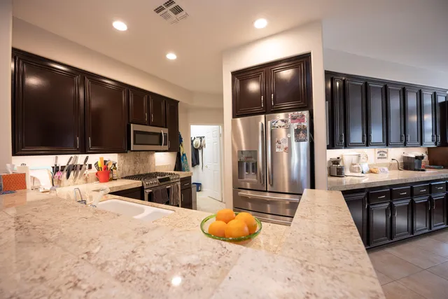 a kitchen with stainless steel appliances kitchen island granite countertop a refrigerator and a sink