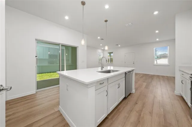 a large kitchen with a sink and wooden floor