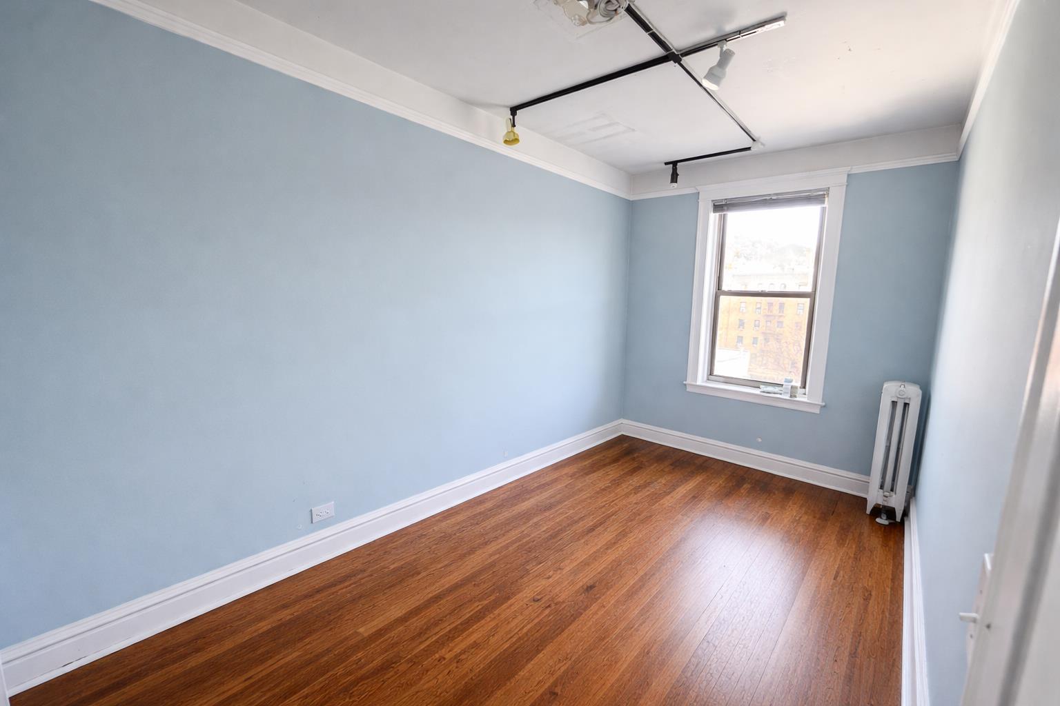1825 Riverside Drive, Unit 5B Manhattan, NY 10034 - Photo 6 of 19 an empty room with wooden floor and windows