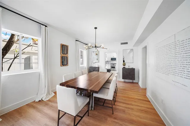 a large kitchen with stainless steel appliances granite countertop a stove top oven a sink dishwasher and white cabinets with wooden floor