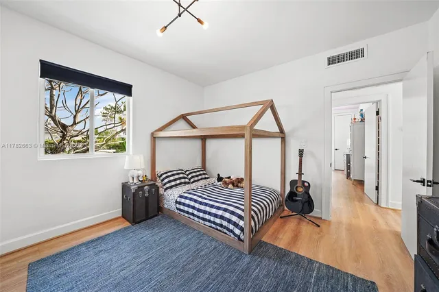 a view of a white house in front of a big yard with large trees