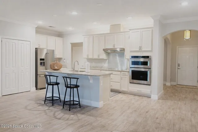 a kitchen with a refrigerator a stove and white cabinets