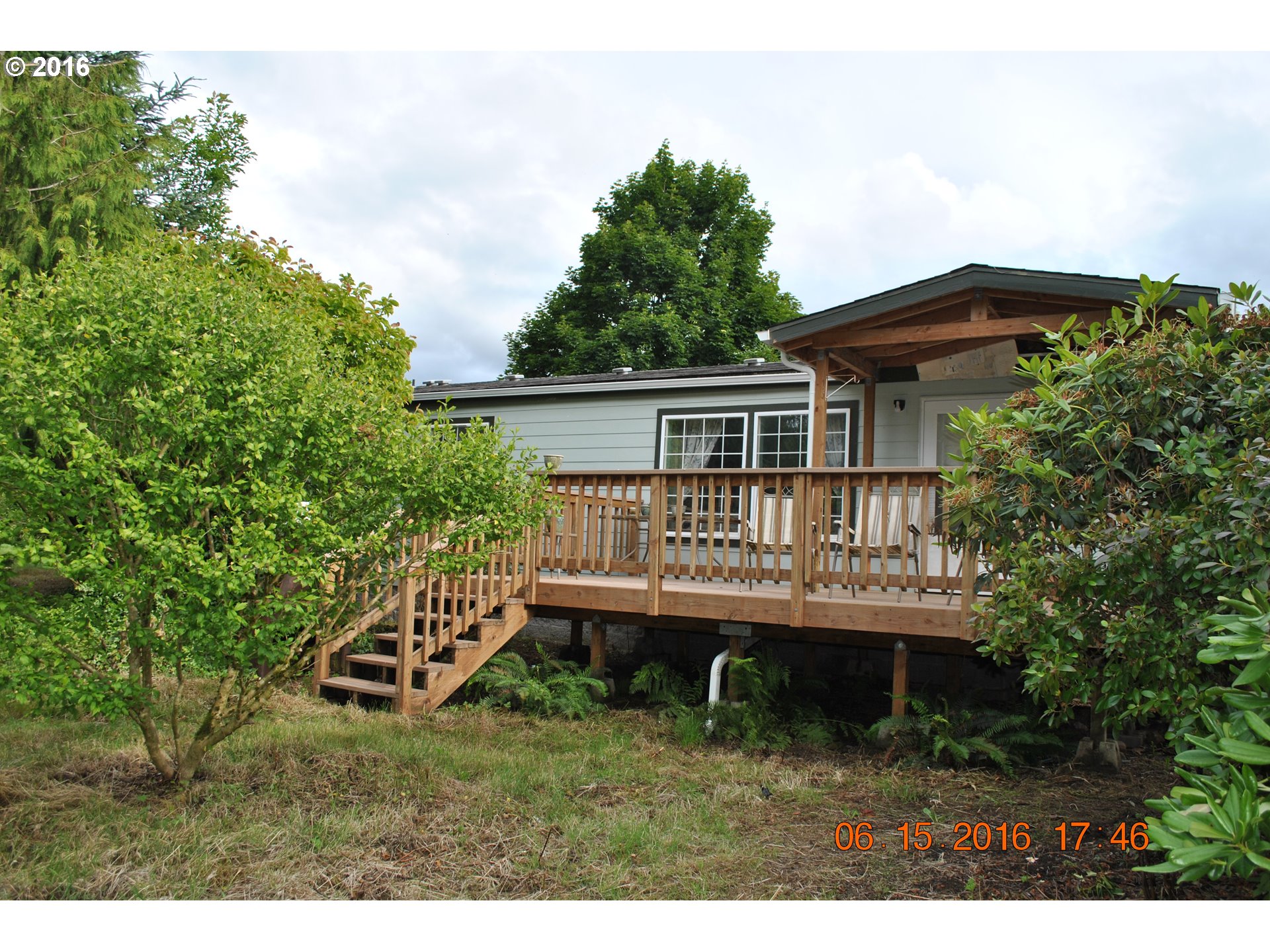 a view of house with a deck and a yard