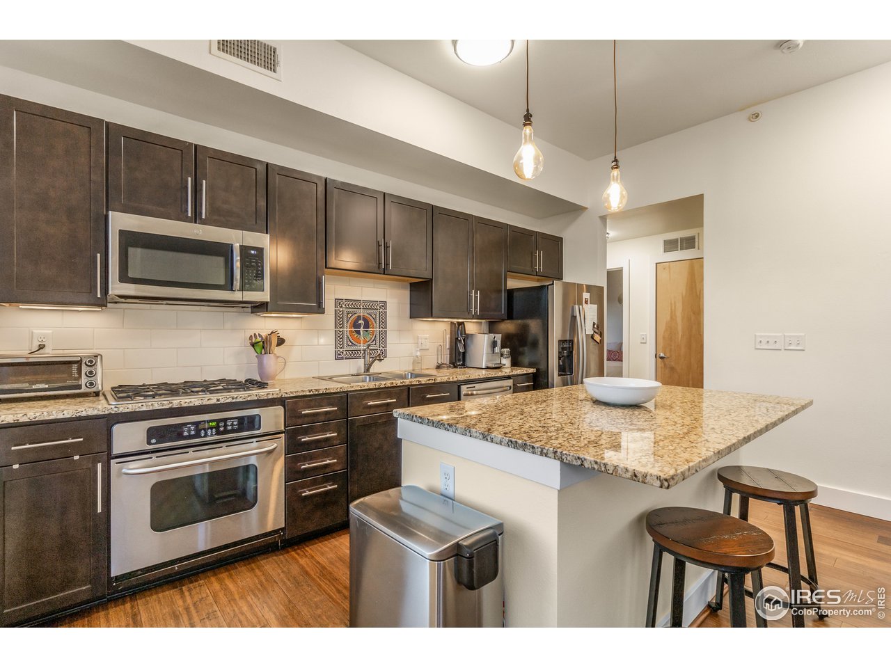 204 Maple Street, Unit 301 Fort Collins, CO 80521 - Photo 11 of 26 a kitchen with kitchen island granite countertop stainless steel appliances a stove sink microwave and cabinets