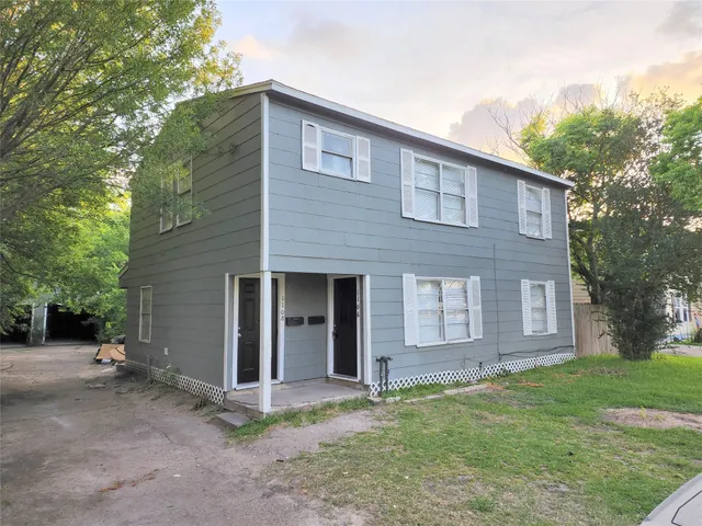 a view of a house with a yard and large tree