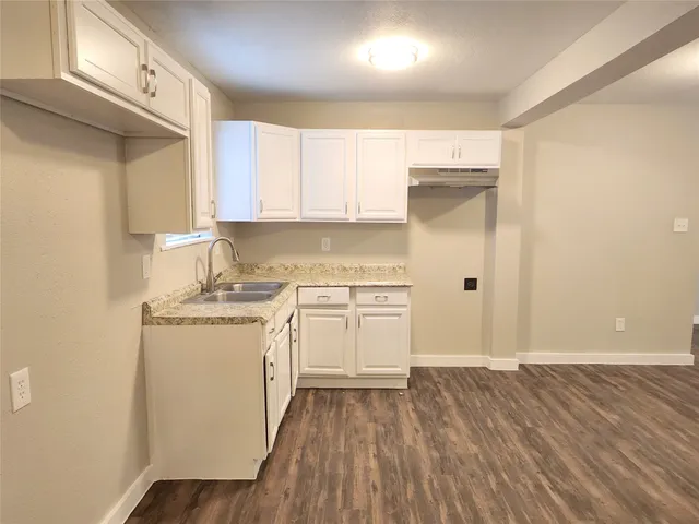 a kitchen with a sink a stove cabinets and wooden floor