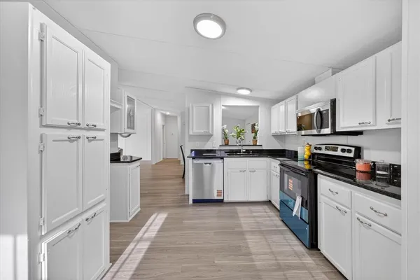 a kitchen with white cabinets and appliances