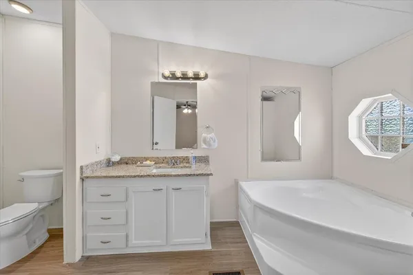 a bathroom with a granite countertop sink a toilet and a mirror