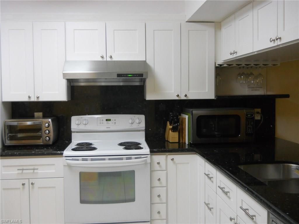 4010 Ice Castle Way, Unit 7 Naples, FL 34112 - Photo 5 of 14 a kitchen with granite countertop white cabinets and black appliances