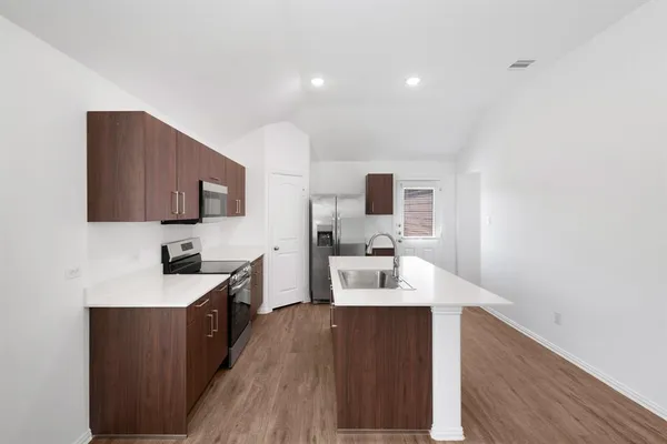 a kitchen with a sink a stove cabinets and wooden floor