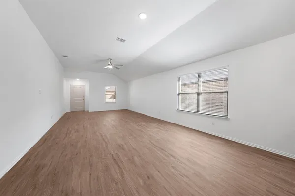 an empty room with wooden floor and windows