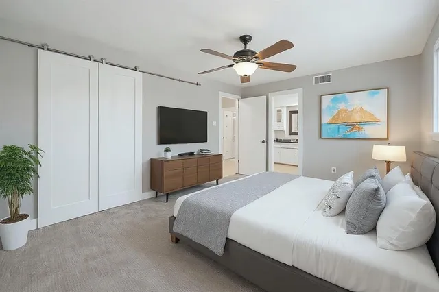 a bedroom with a bed a flat screen tv and a potted plant