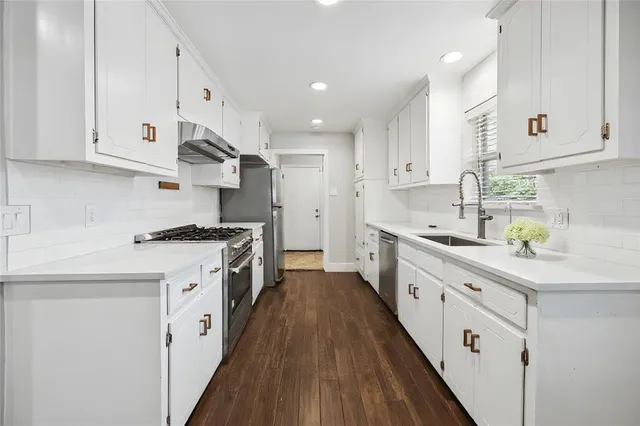 a kitchen with granite countertop a sink a counter space stainless steel appliances and cabinets