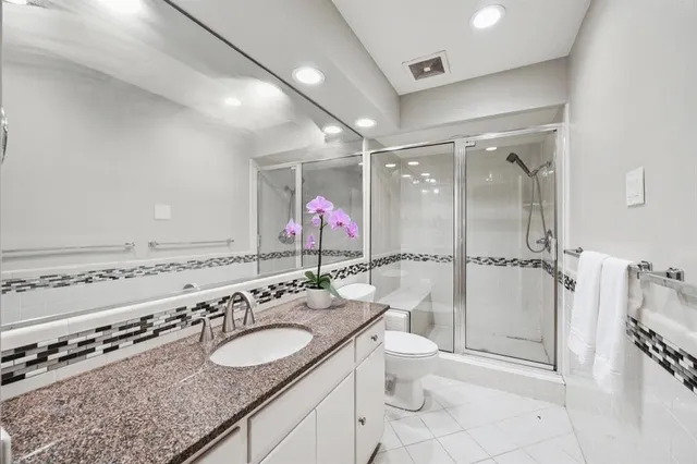 a bathroom with a granite countertop sink mirror vanity and toilet