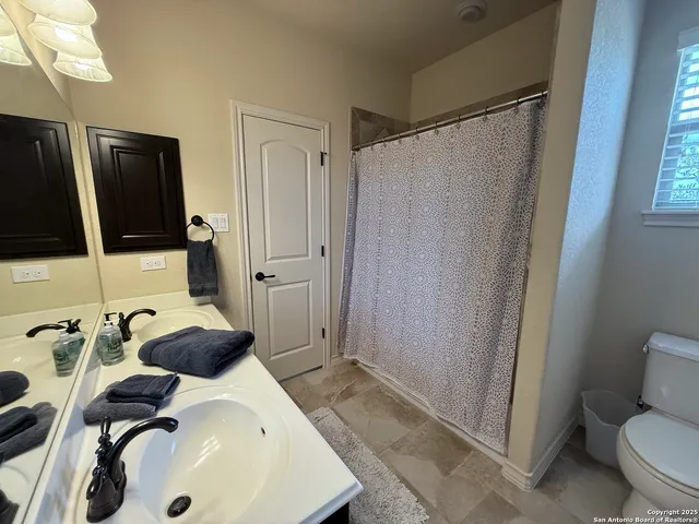 a bathroom with a sink a toilet a mirror and shower