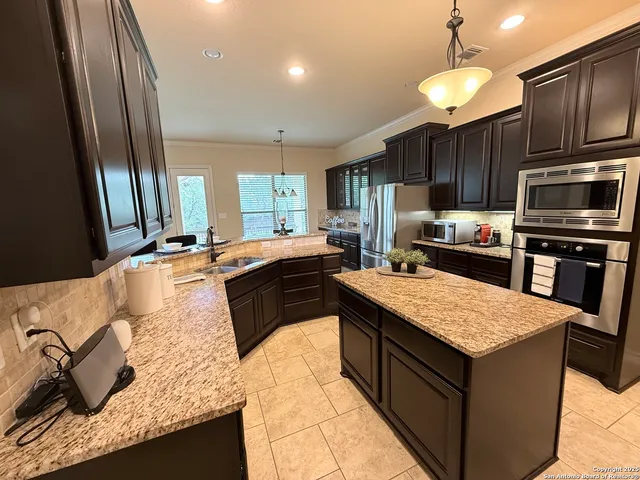 a kitchen with kitchen island granite countertop a sink counter top space appliances and cabinets