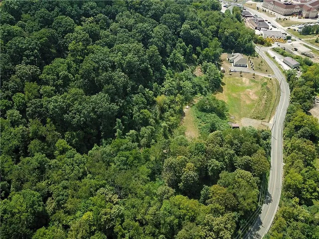 an aerial view of residential house with outdoor space and trees all around