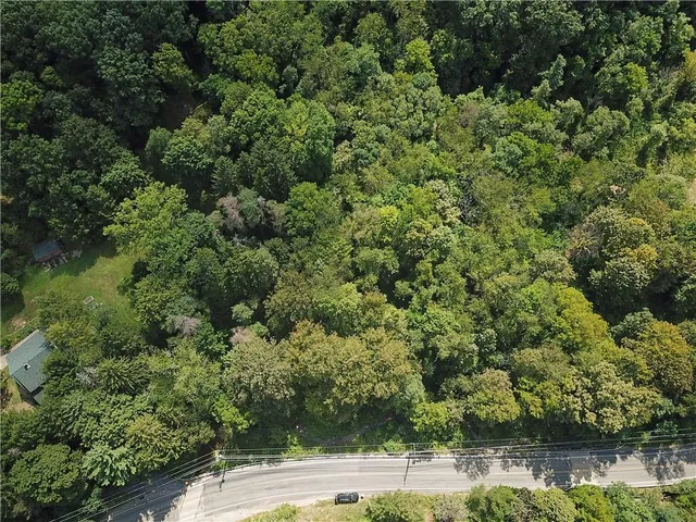 an aerial view of residential house with outdoor space and trees all around