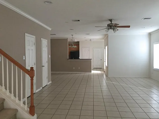 an empty room with chandelier fan and windows
