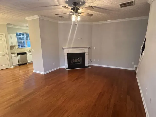 a view of an empty room with wooden floor fireplace and a window