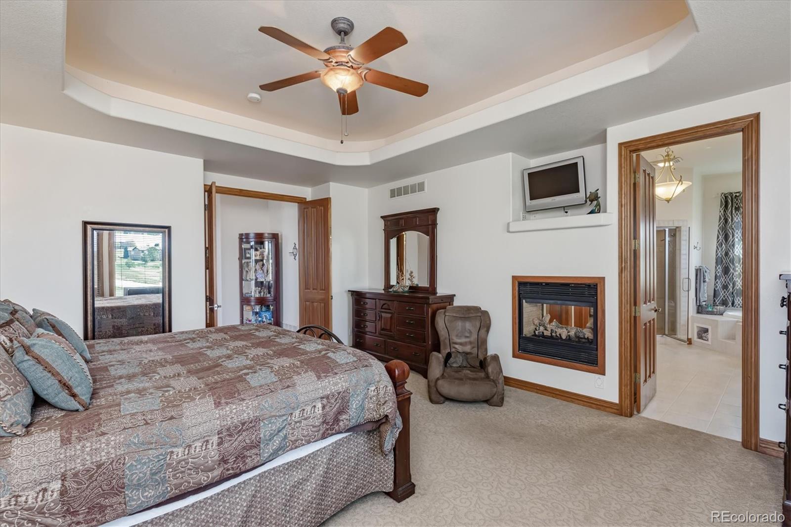 12080 Summit Ridge Road Parker, CO 80138 - Photo 22 of 39 a spacious bedroom with a bed and a fireplace