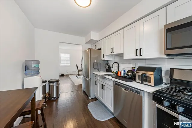 a kitchen with granite countertop a stove top oven a sink dishwasher a dining table and chairs with wooden floor