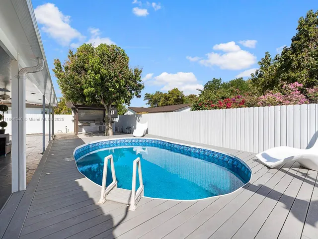 a view of swimming pool on a sunny day with lawn chairs