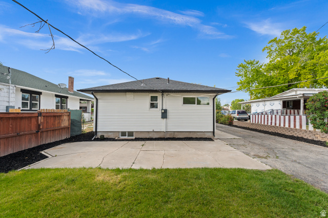 189 West Center Street Midvale, UT 84047 - Photo 59 of 64 Rear exterior featuring white vinyl siding, a black shingle roof, a concrete patio, and a grass lawn