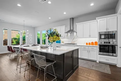 a kitchen with stainless steel appliances a stove a sink a microwave a dining table and chairs