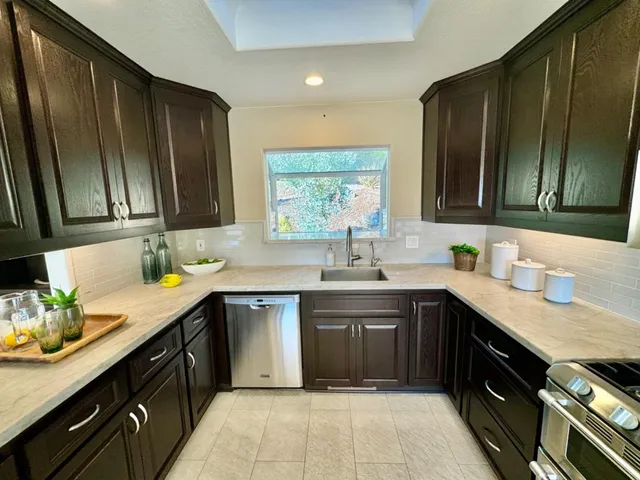 a kitchen with a sink dishwasher a stove top oven a refrigerator with wooden cabinets and floor