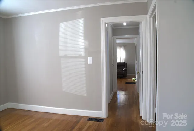a view of a hallway with wooden floor and a bathroom