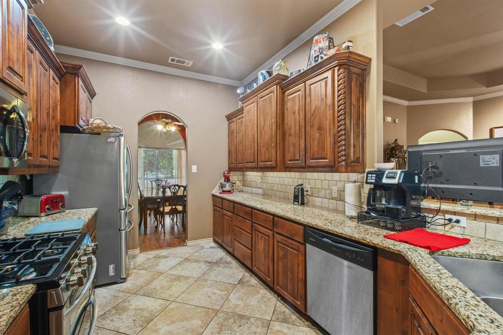 112 Knight Court Springtown, TX 76082 - Photo 9 of 26 Kitchen featuring wood cabinetry, granite countertops, tile flooring, stainless steel appliances, and recessed lighting