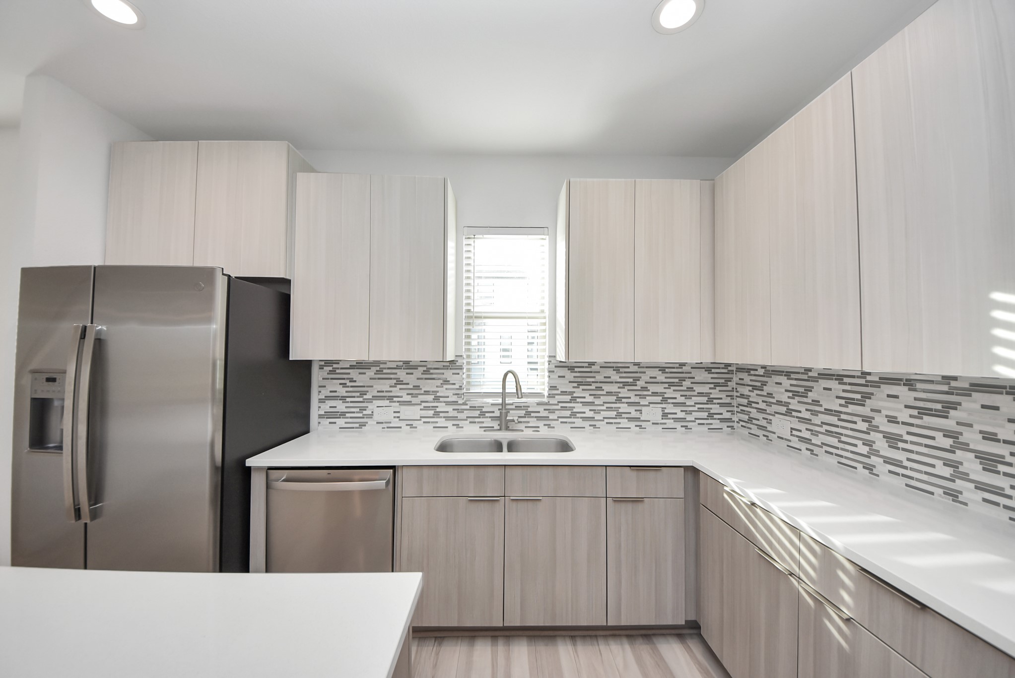 18716 Centro Main Street Conroe, TX 77385 - Photo 26 of 50 Modern kitchen with sleek cabinetry, quartz countertops, stainless steel appliances, and a contemporary tile backsplash.