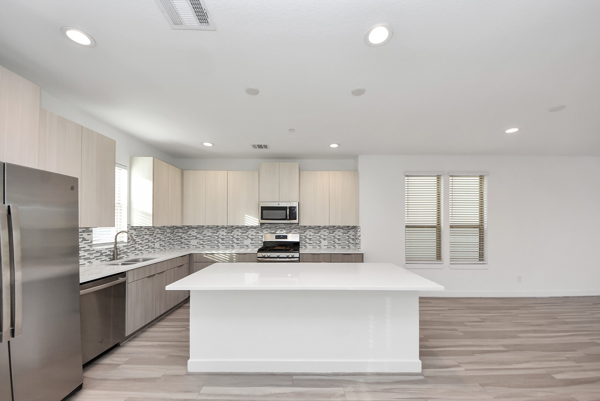 18716 Centro Main Street Conroe, TX 77385 - Photo 31 of 50 Well-appointed kitchen featuring stainless steel gas range, built-in microwave, quartz countertops, and designer backsplash, anchored by a spacious island ideal for gatherings.