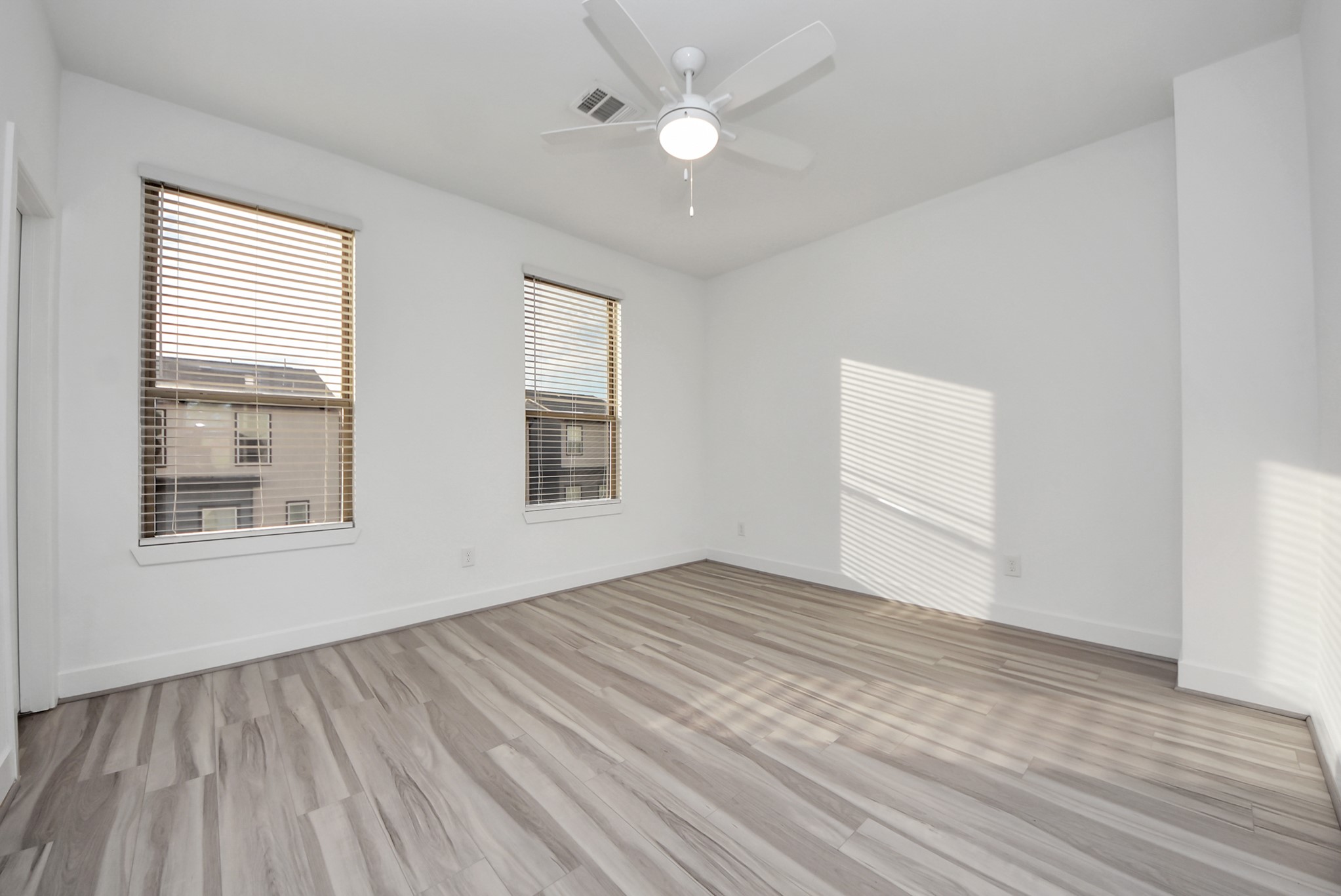 18716 Centro Main Street Conroe, TX 77385 - Photo 40 of 50 Light-filled secondary bedroom with wide-plank flooring, neutral walls, ceiling fan, and generous windows that provide natural light and a comfortable retreat.