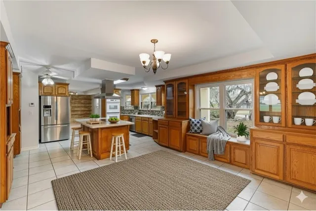 a large living room with stainless steel appliances granite countertop furniture a fireplace and a large window