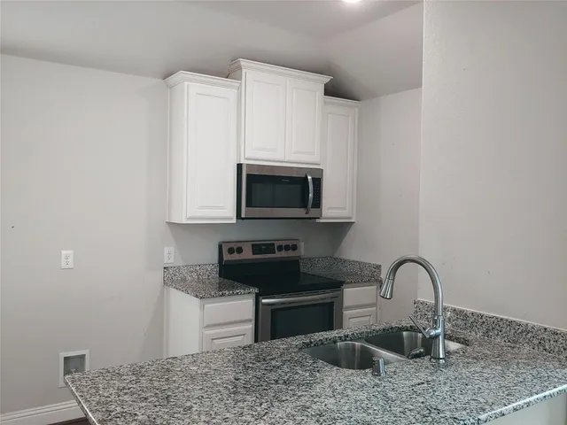 a kitchen with granite countertop white cabinets and stainless steel appliances