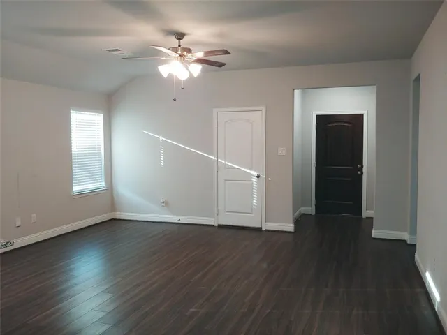 an empty room with wooden floor closet and windows