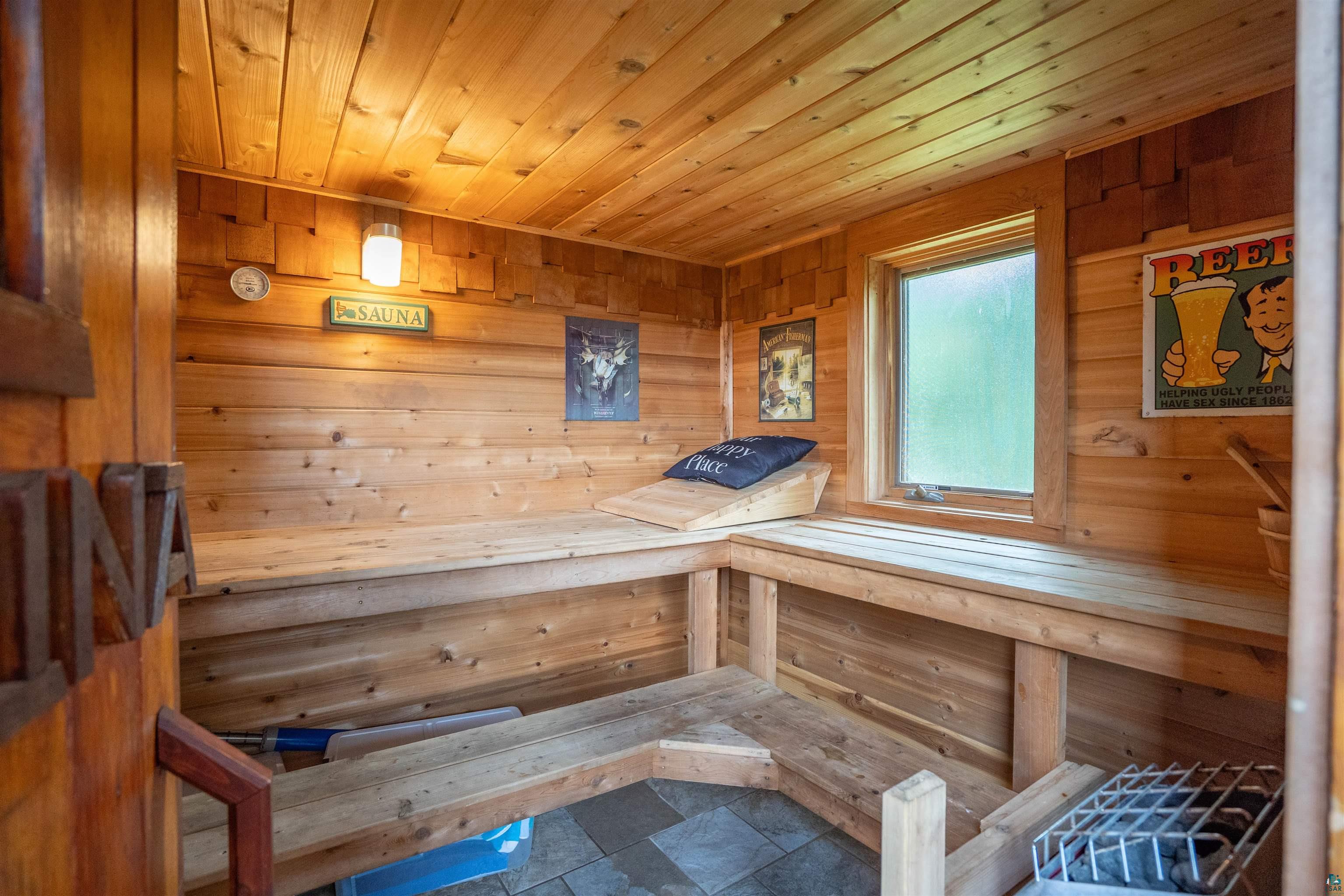 11911 East Rowe Road Lake Nebagamon, WI 54849 - Photo 32 of 61 Wood-paneled sauna featuring a built-in multi-level bench, a frosted window, a light fixture, and a floor-mounted heater
