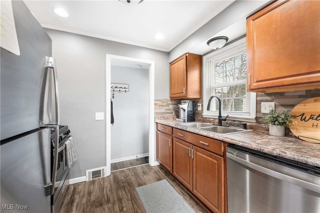 2908 19th Street Northwest Canton, OH 44708 - Photo 16 of 45 Kitchen with decorative backsplash, baseboards, stainless steel appliances, dark wood-type flooring, and a sink