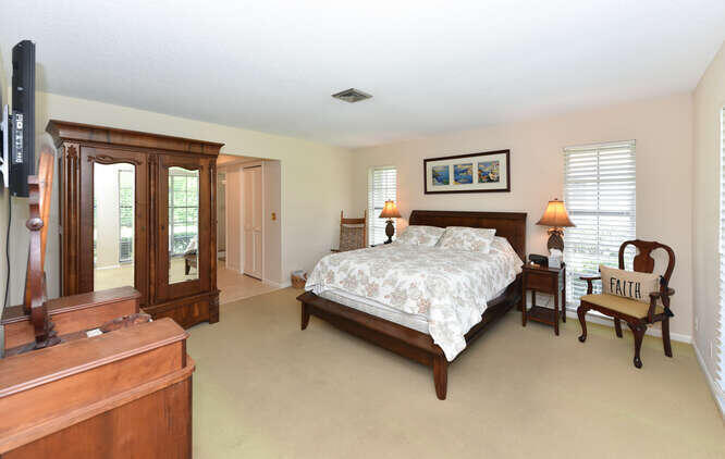 493 Forestview Drive Atlantis, FL 33462 - Photo 19 of 27 a bedroom with a bed and dresser with mirror
