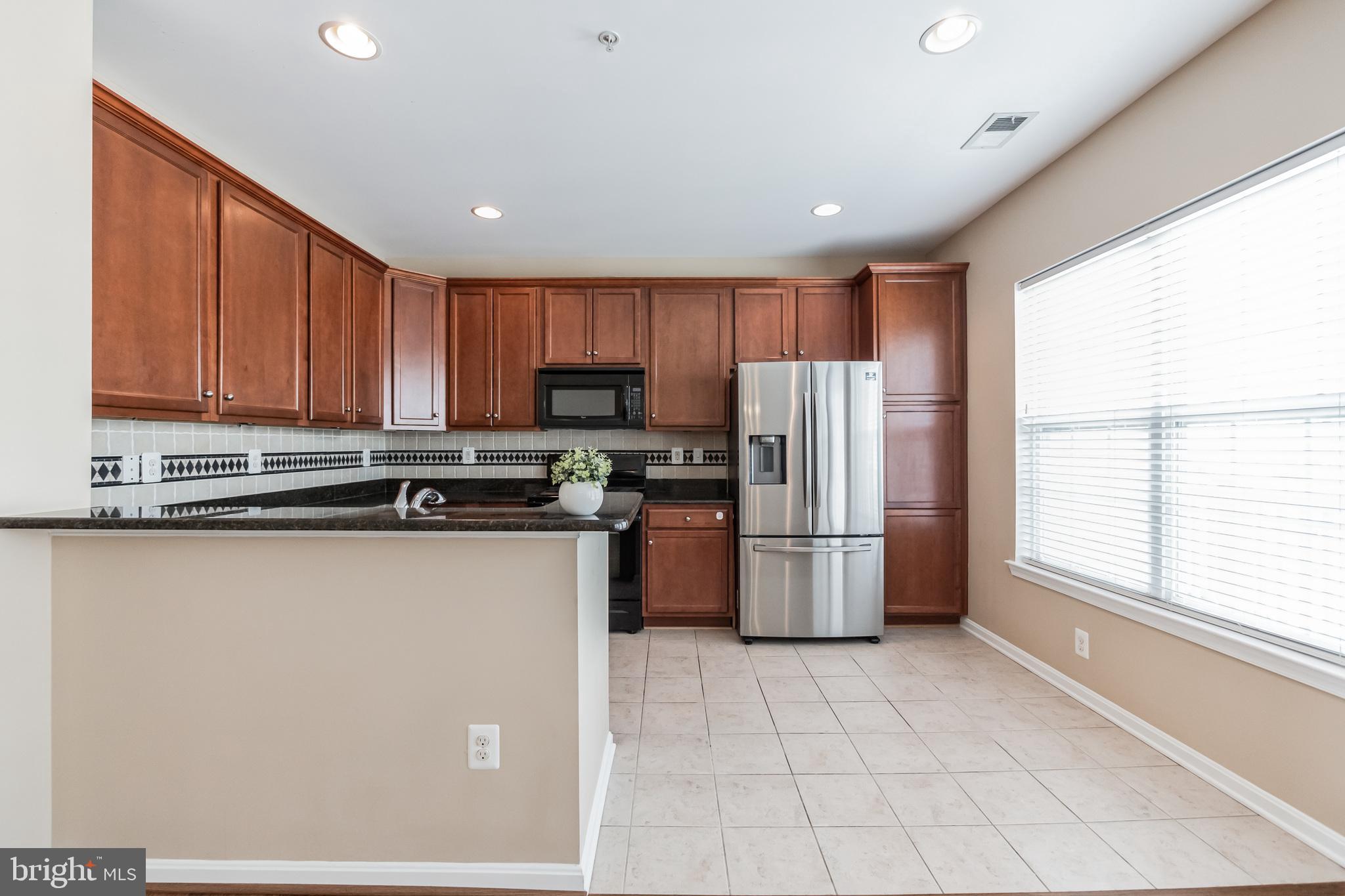 1834 Monocacy View Circle, Unit 53B Frederick, MD 21701 - Photo 11 of 30 a kitchen with a refrigerator a stove top oven a sink and dishwasher with wooden floor